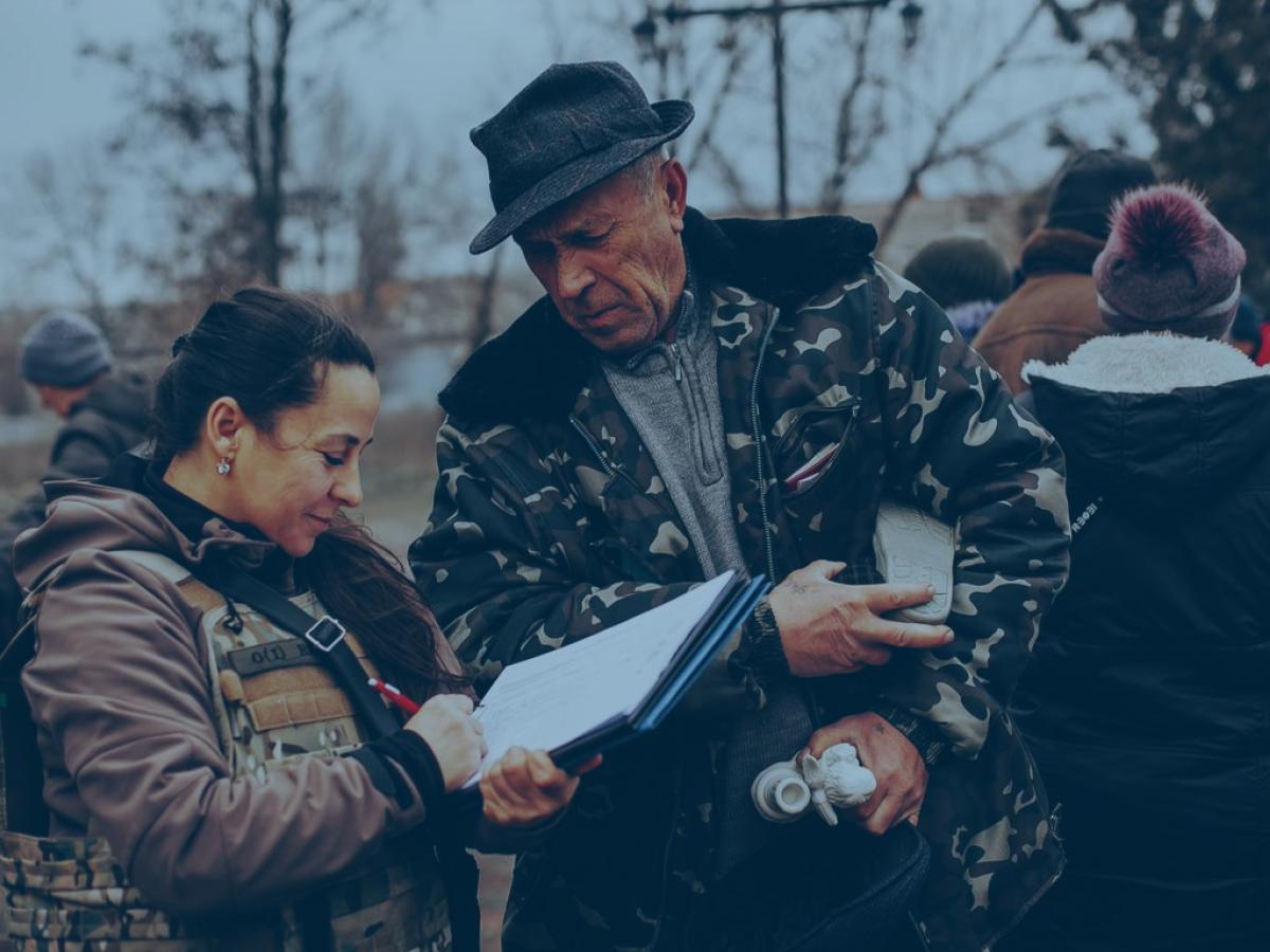 An aid worker and a local resident consult a list as they stand outside in a battle-affected town.