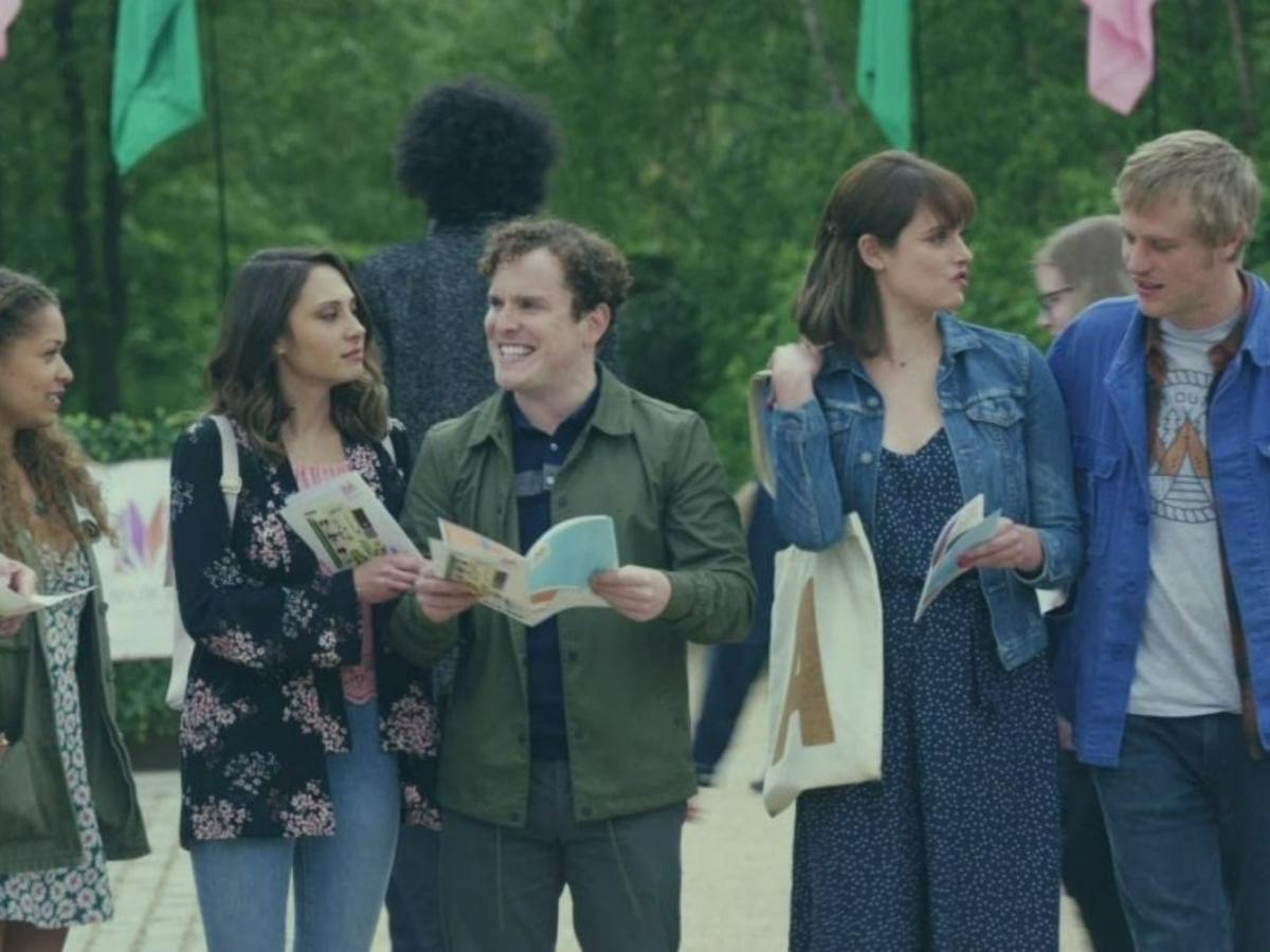 A row of young people stand and talk to each other