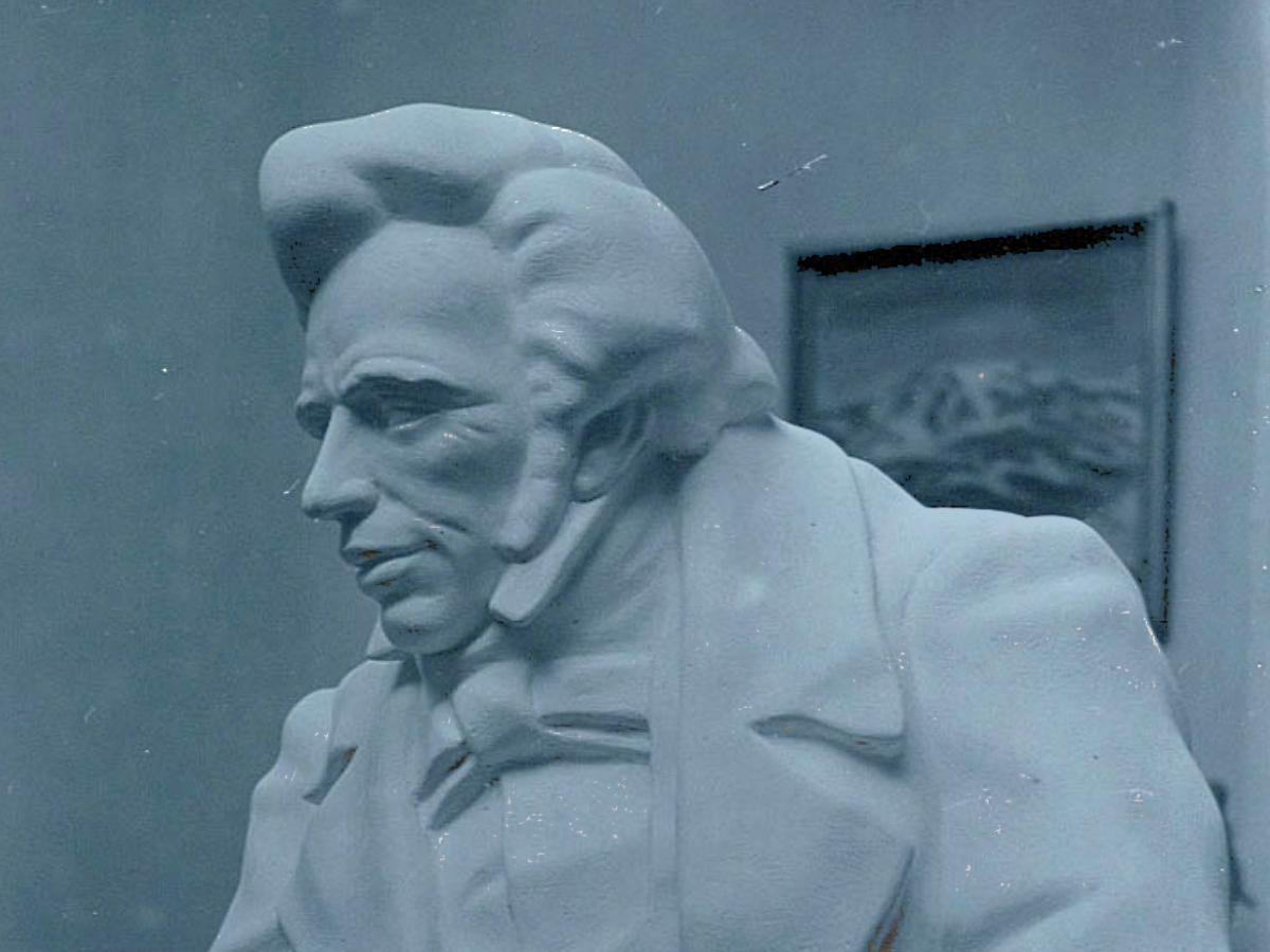 A sculpture of a early 19th century man with a quiff and sharp suit.