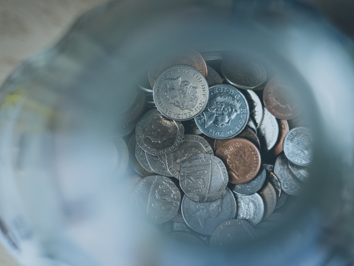 A pile of coins in focus at the bottom of an out of focus glass tube.