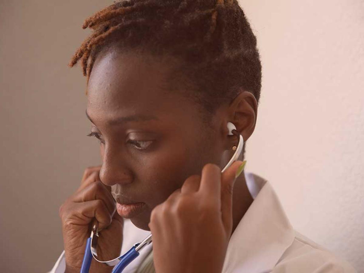 A doctor looks thoughtful will holding a stethoscope to their ears.