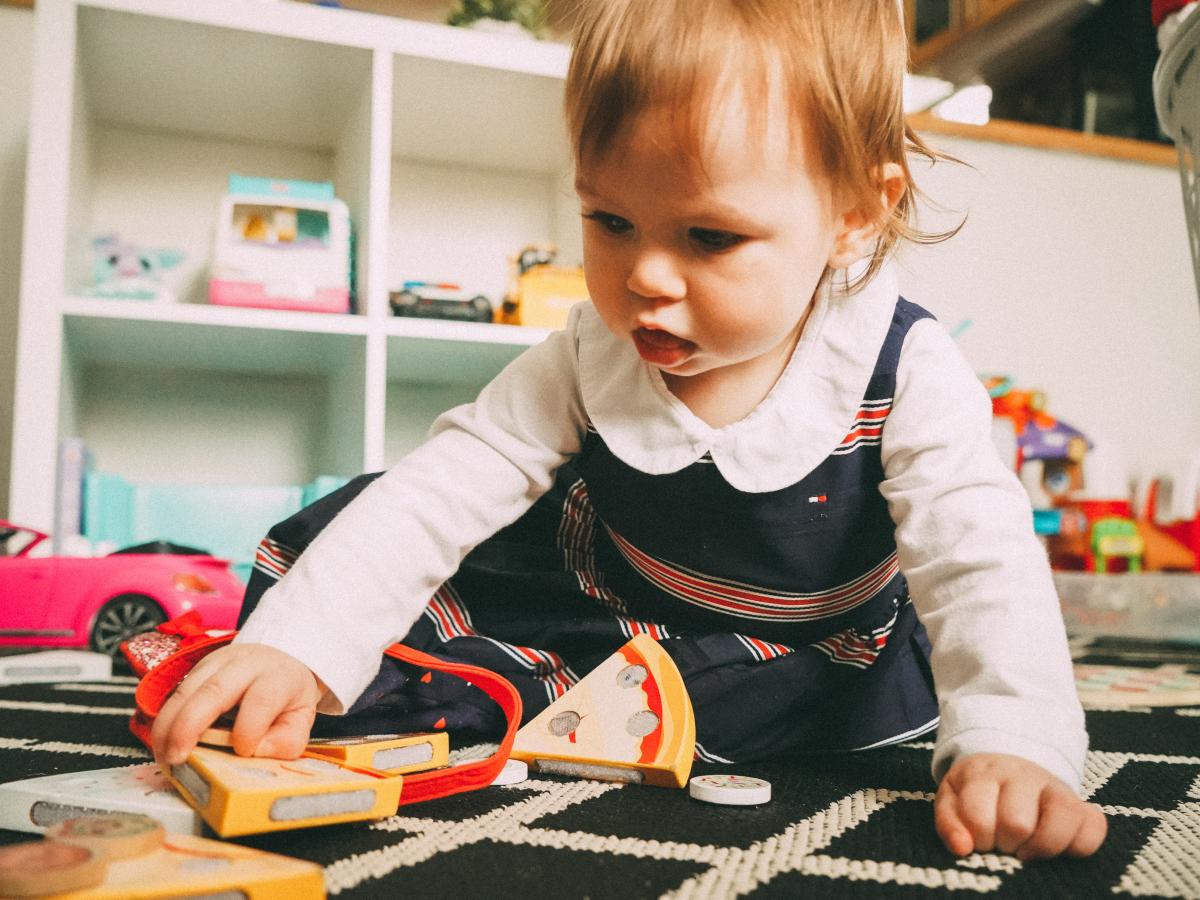 A baby plays with wooden toys on a carpert.