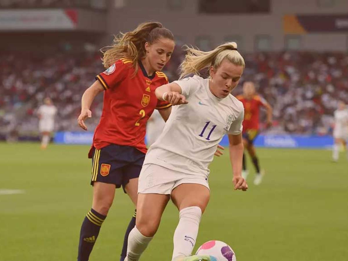 Two footballers run in step as one tries to tackle the other