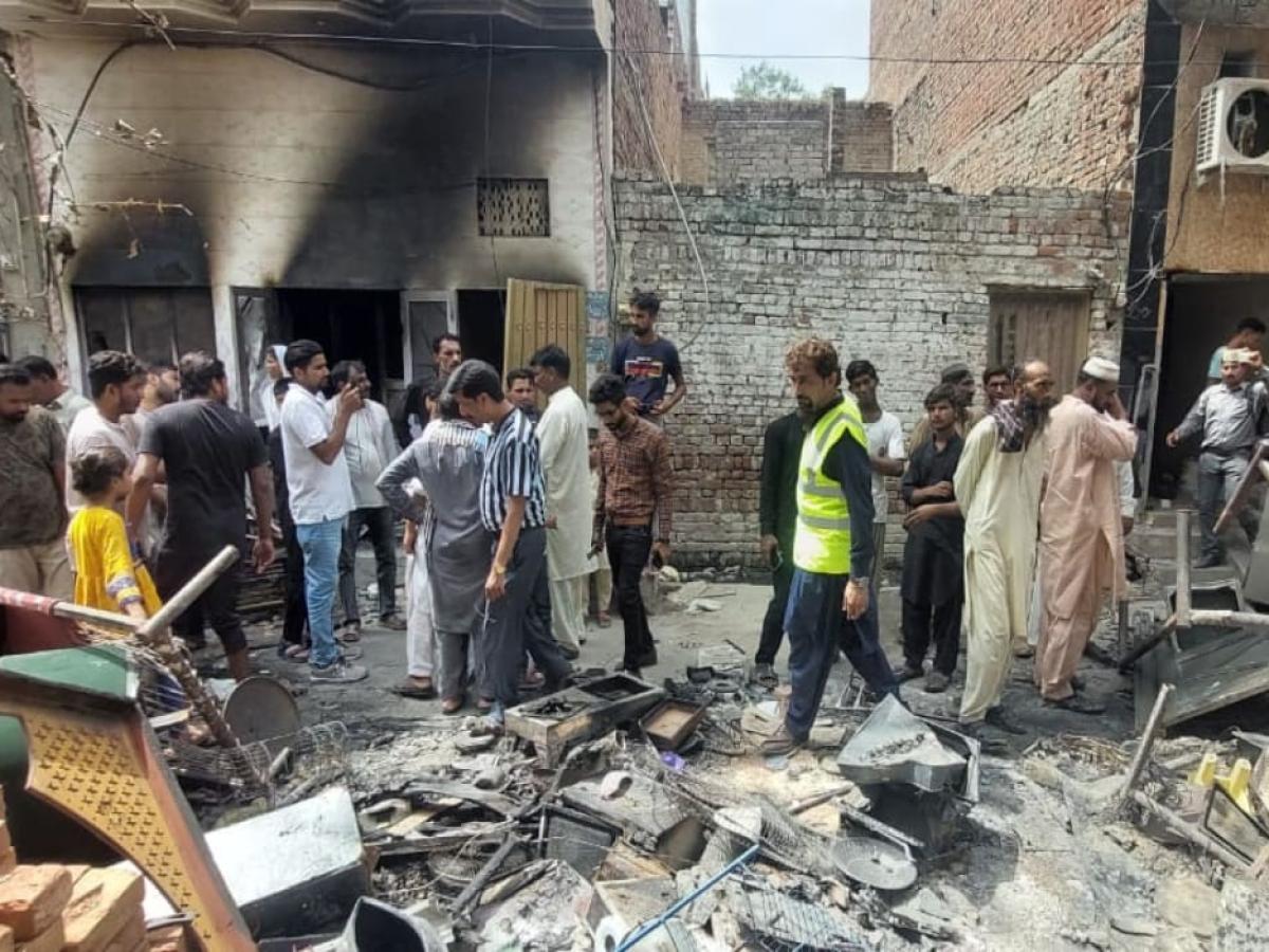 A crowd of people inspect fire damaged debris outside a burnt-out church.