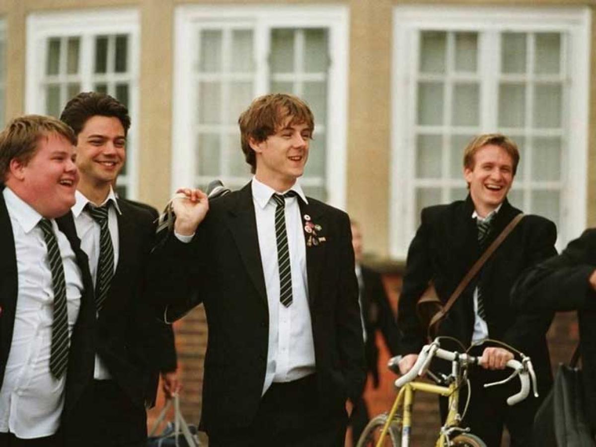 School students walk across a playground confidently talking and laughing with us