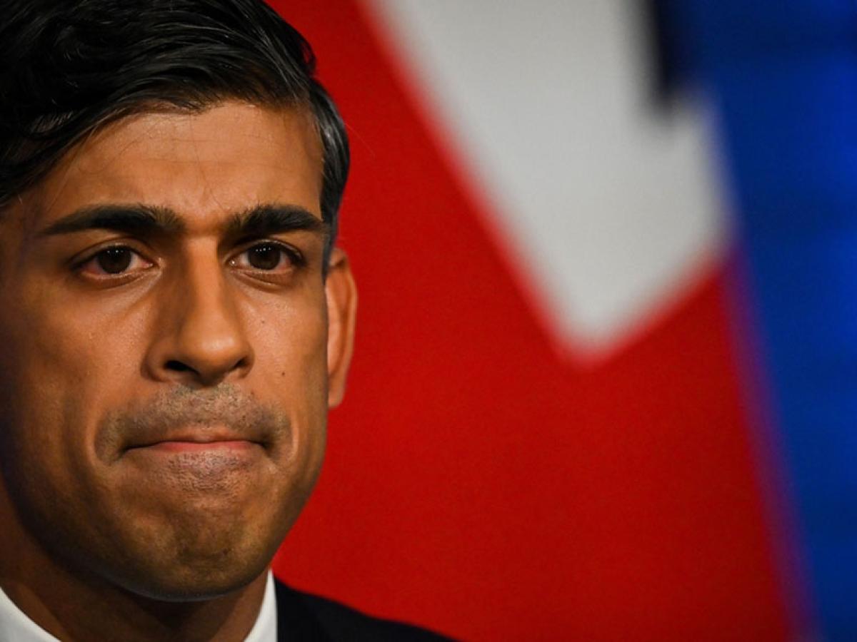 A cropped image of the face of RIshi Sunak with colours of a flag behind him