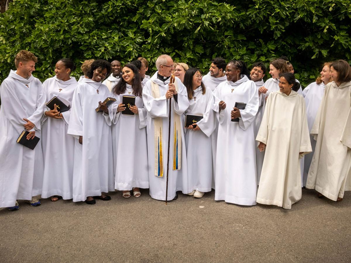 A group of young people wearing white habits stand and laugh with each other.