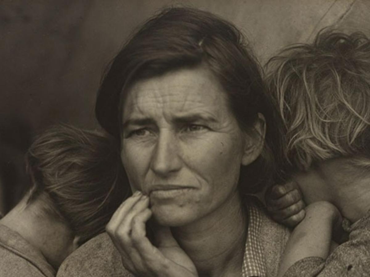 A black and white close up of a mothers cradling her jaw in worry as children cuddle into her.