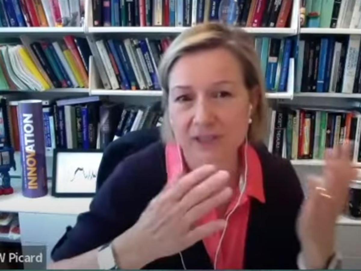 a woman at a desk video call gestures with her hands to make a point.