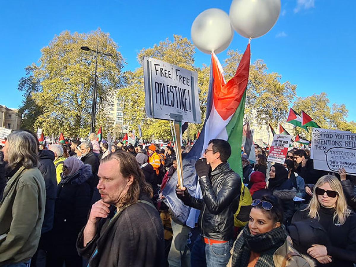 A crowd of people on a protest march file down the street in one directions.