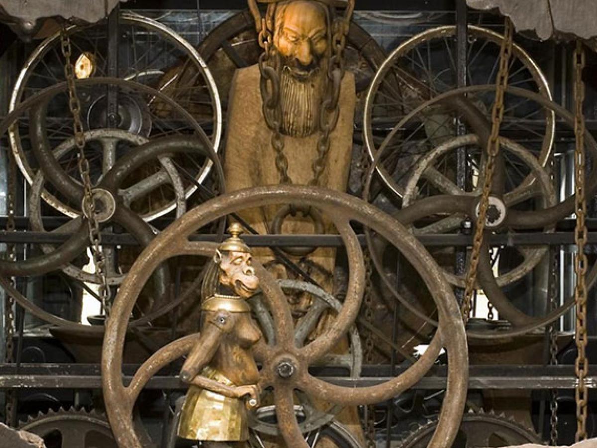 A close-up of a complex clock mechanism featuring small statues within it.