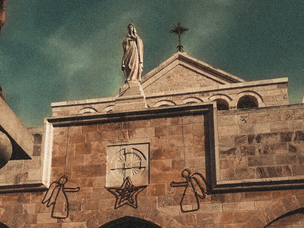 A church gable featuring a cross, a Madonna and angel Christmas decorations.