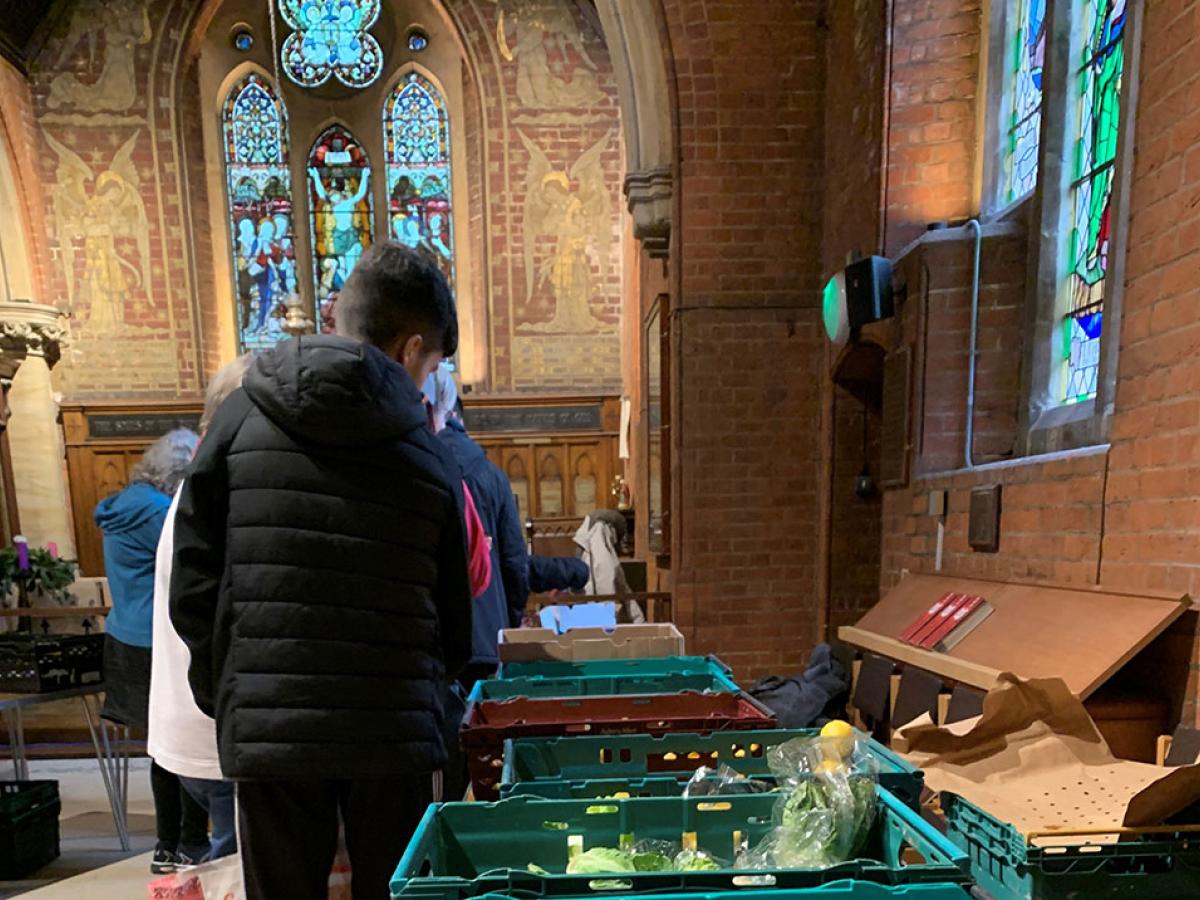 clients of a charity queue beside a table of suppliers in a church