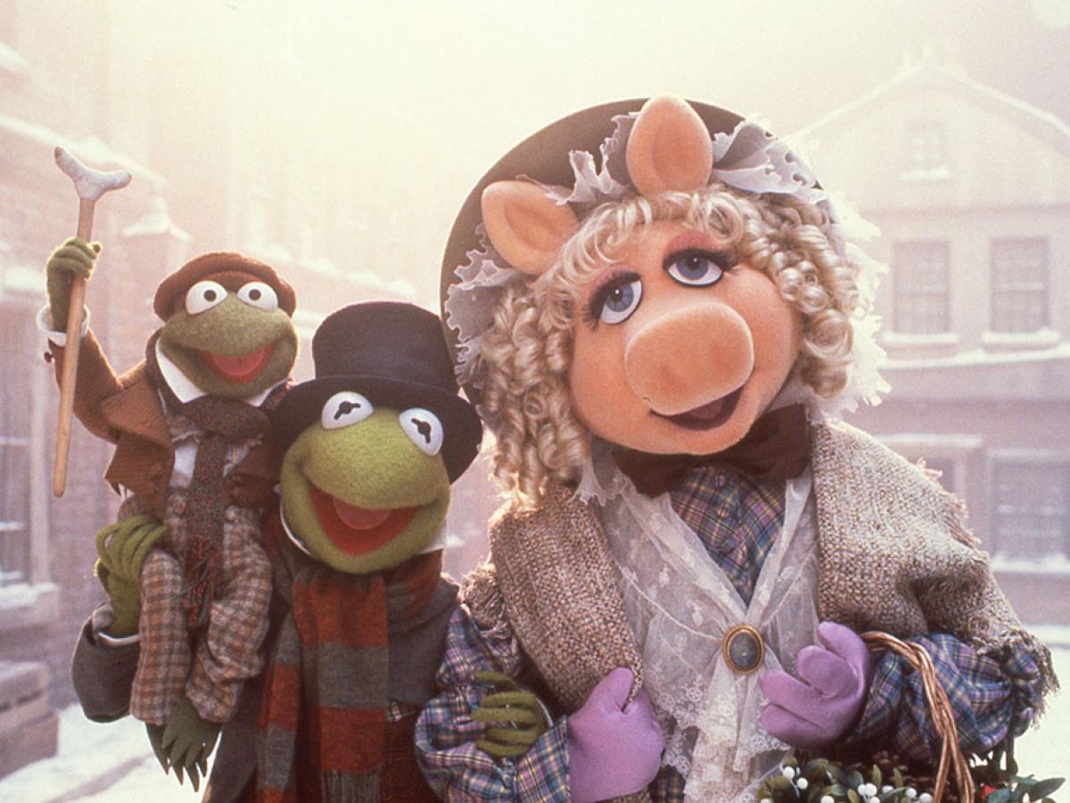 Muppet characters dressed as Dickensian characters stand in a snowy street.