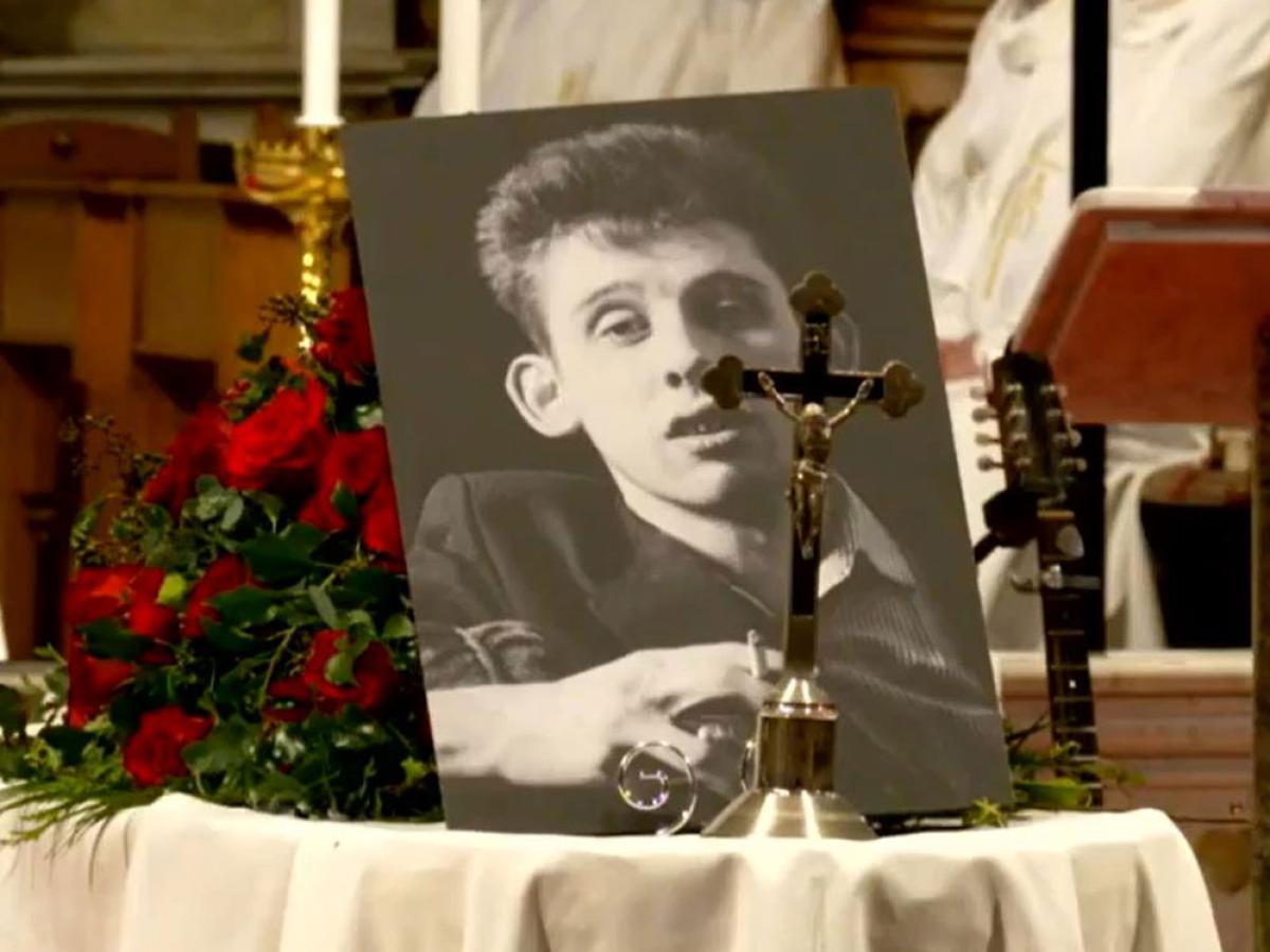 Upon his draped coffin, a picture of Shane MacGowan and a crucifix sit