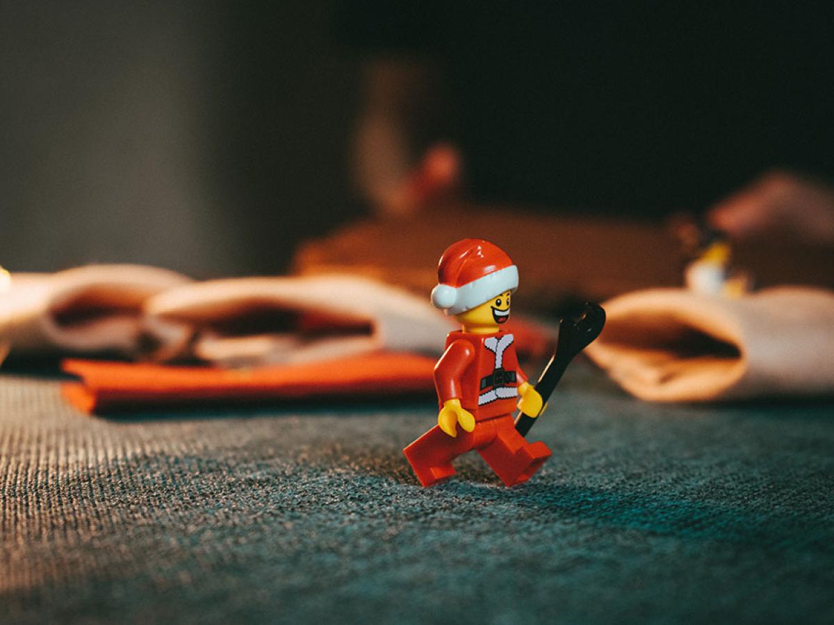 A Lego Stanta figure strolls across a table holding a wrench