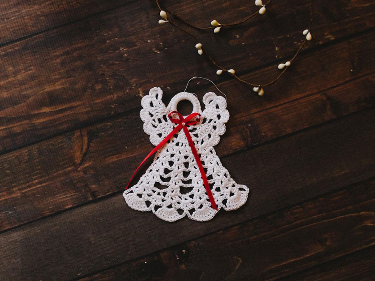 A white crocheted angel decoration against a dark background.