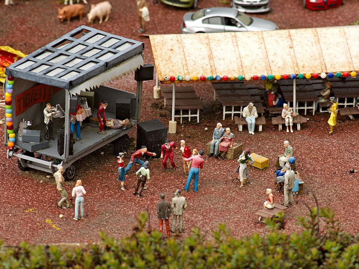 A miniature tableau depicts a band performing at a concert as people dance and others watch from a marque.