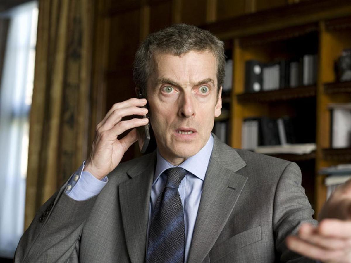 An irate man holds a mobile phone to his ear while gesticulating with his other hand.