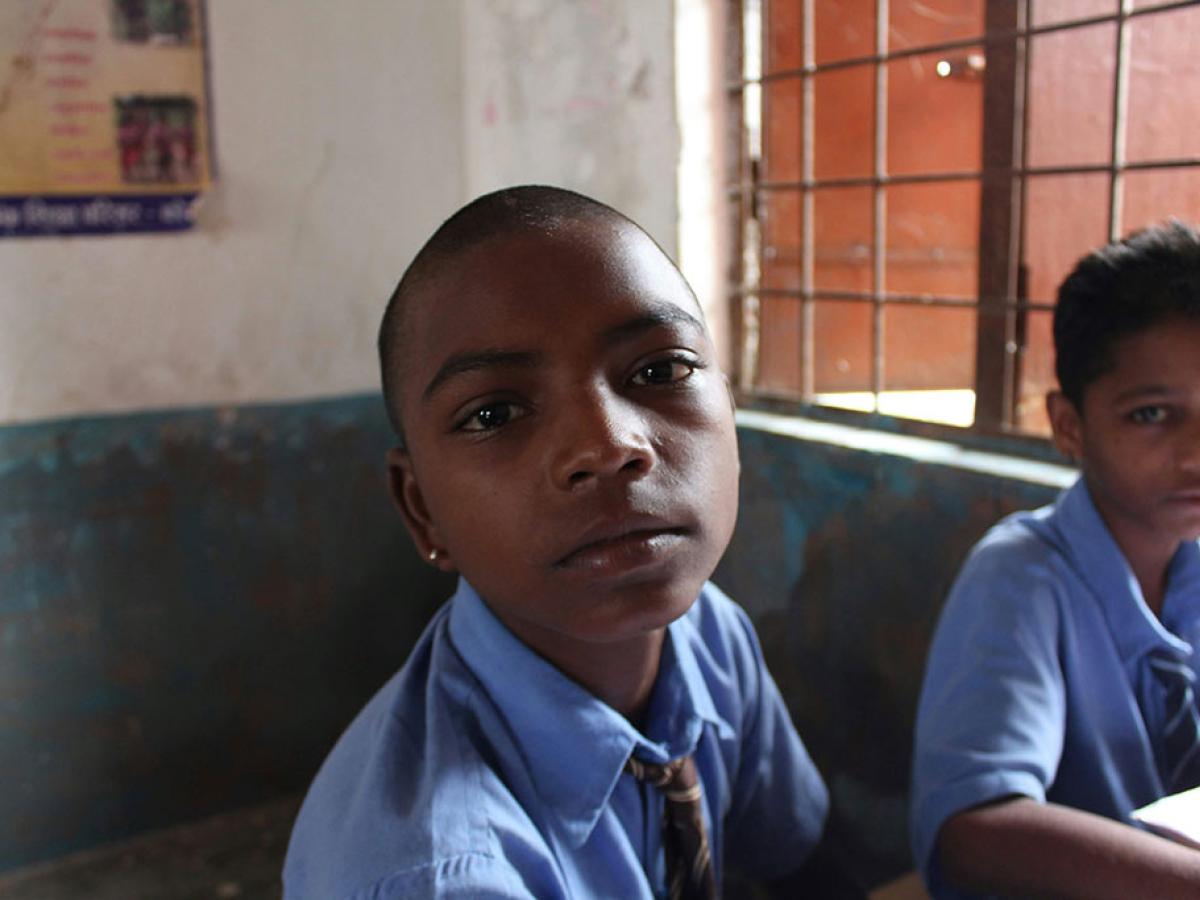 A pupil in a classroom looks around and into the camera.