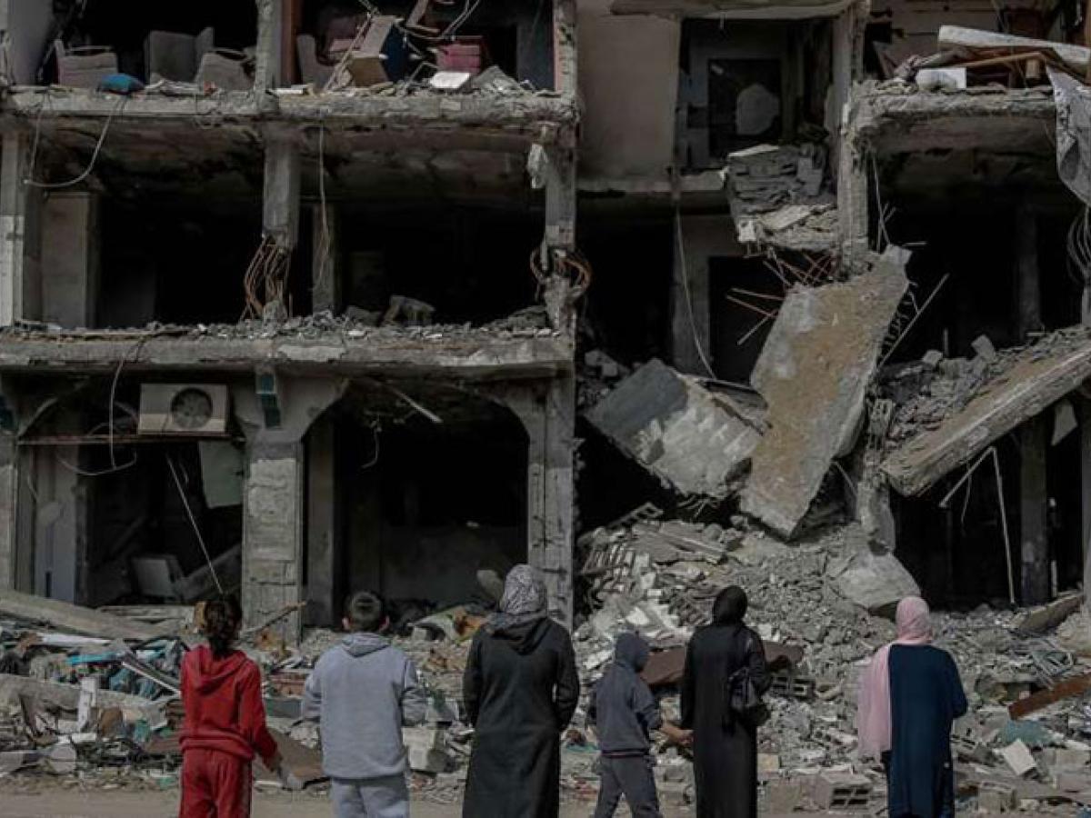 A family look at the concrete shell and remains of a bombed building.