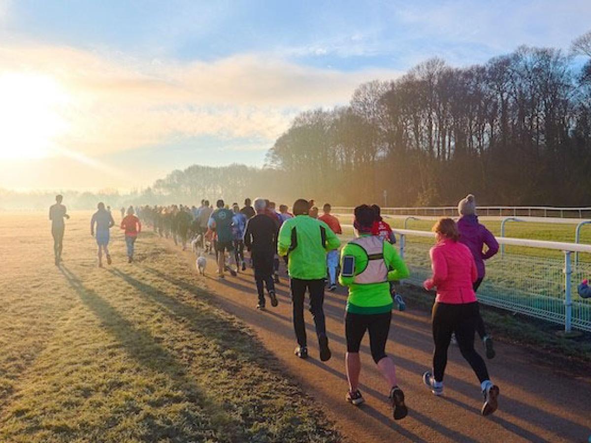 Runners jog along a path into the sunset.