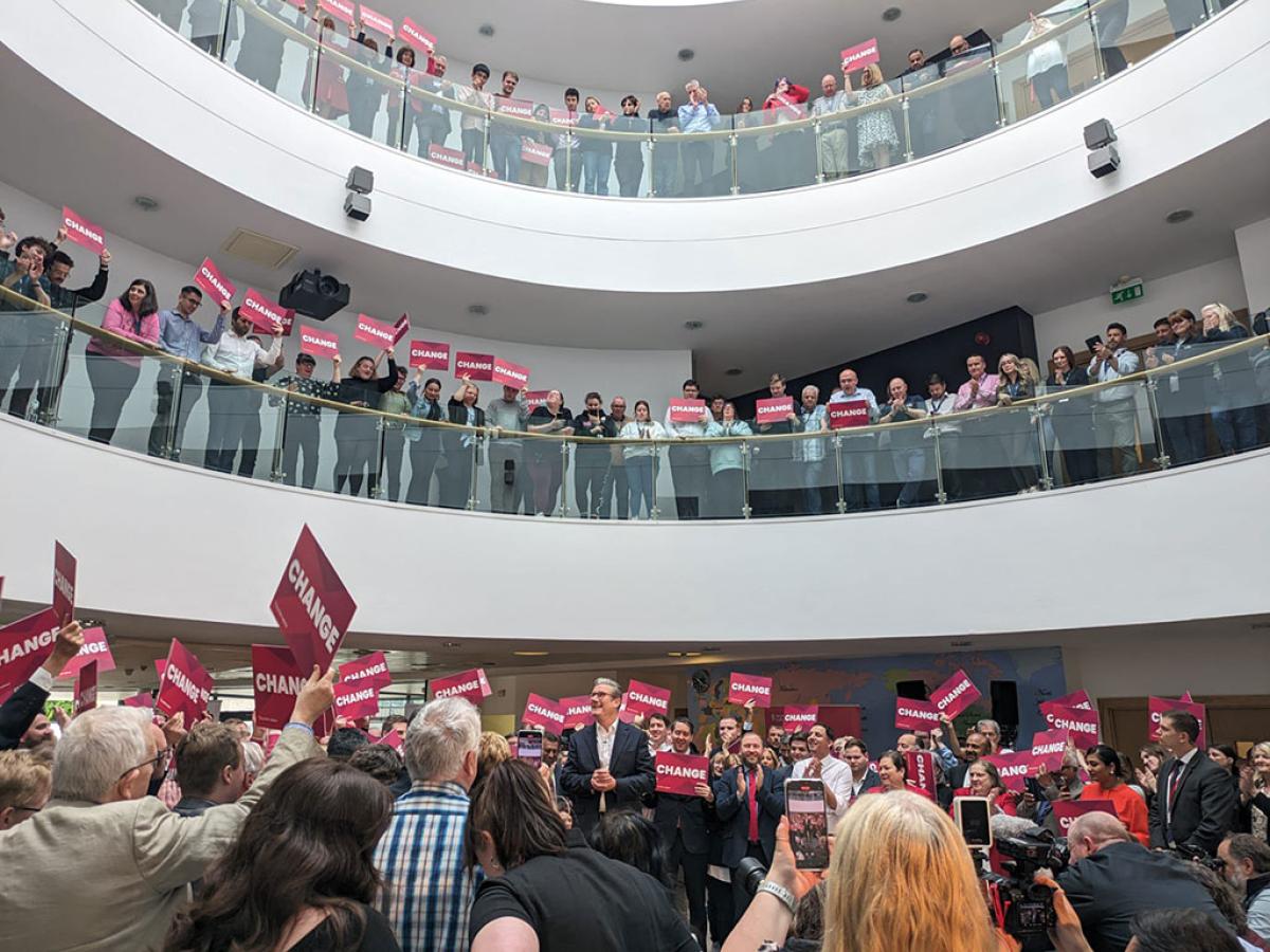 Looked down upon by crowds in galleries, a politician stands amid a throng of supporters