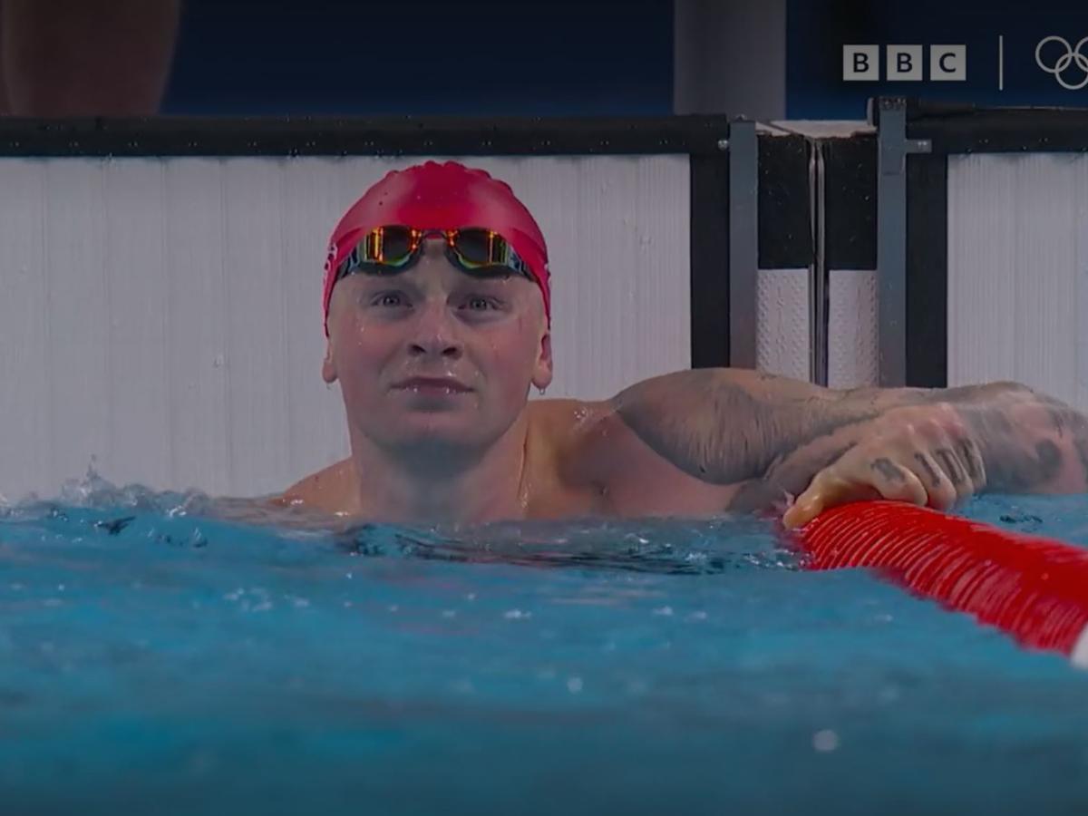 A swimmer at the end of a race, looks to the result screen.