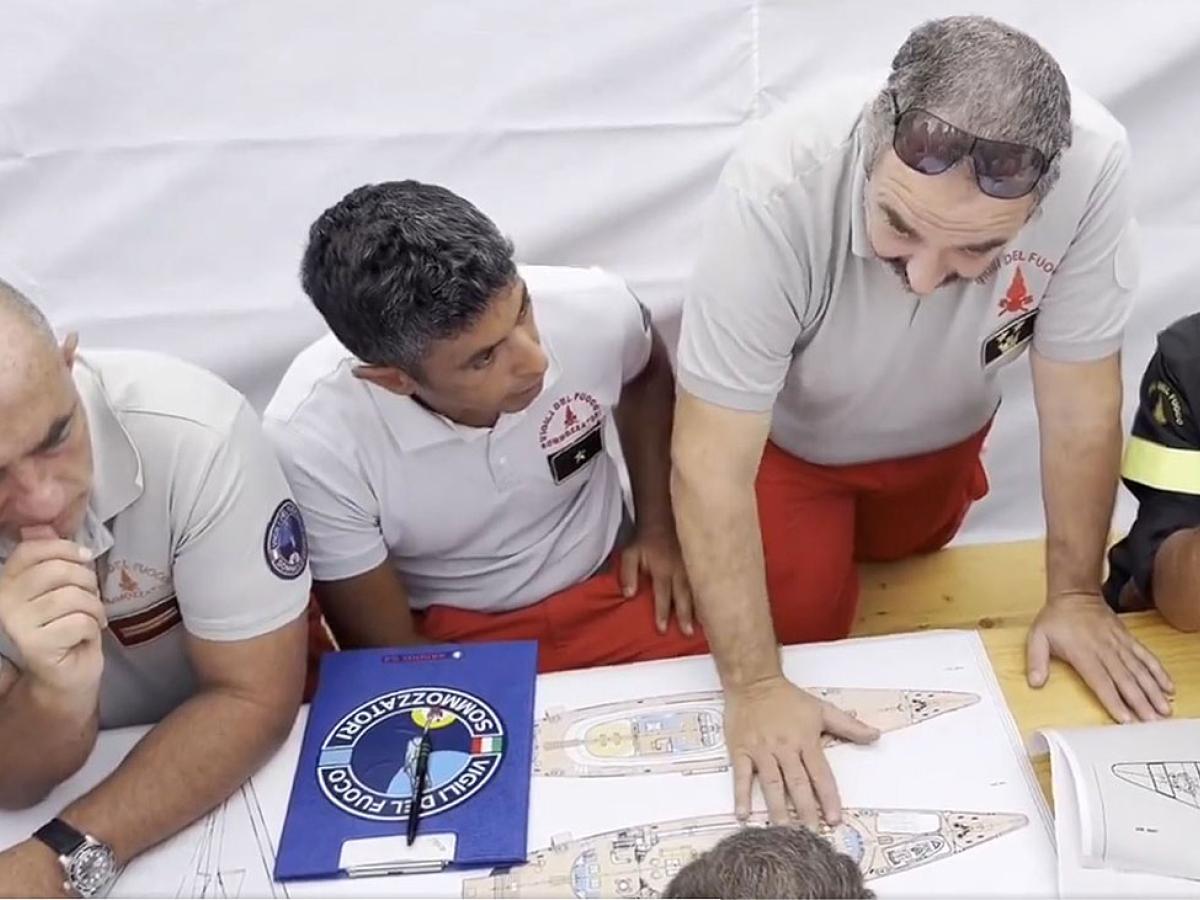 Rescue workers look at the plan of a yacht.