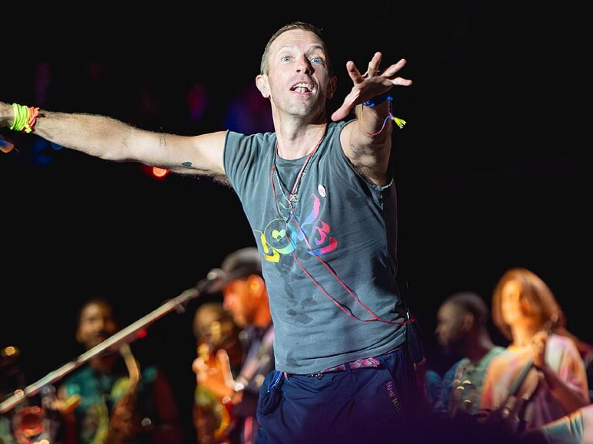 A singer on a stage holds out his arms to conduct the crowd.