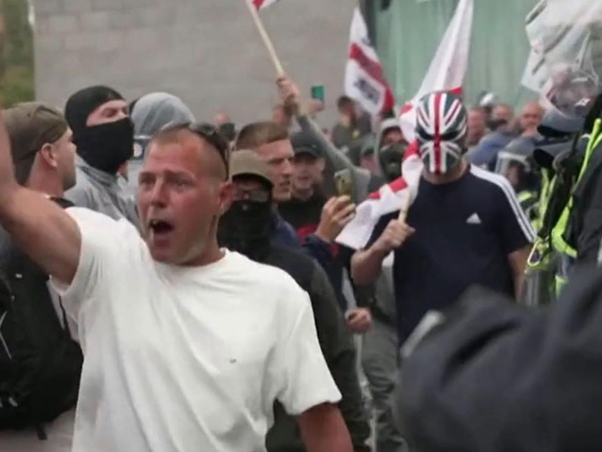 Rioters confront police, one wearing a sinister Union Jack mask