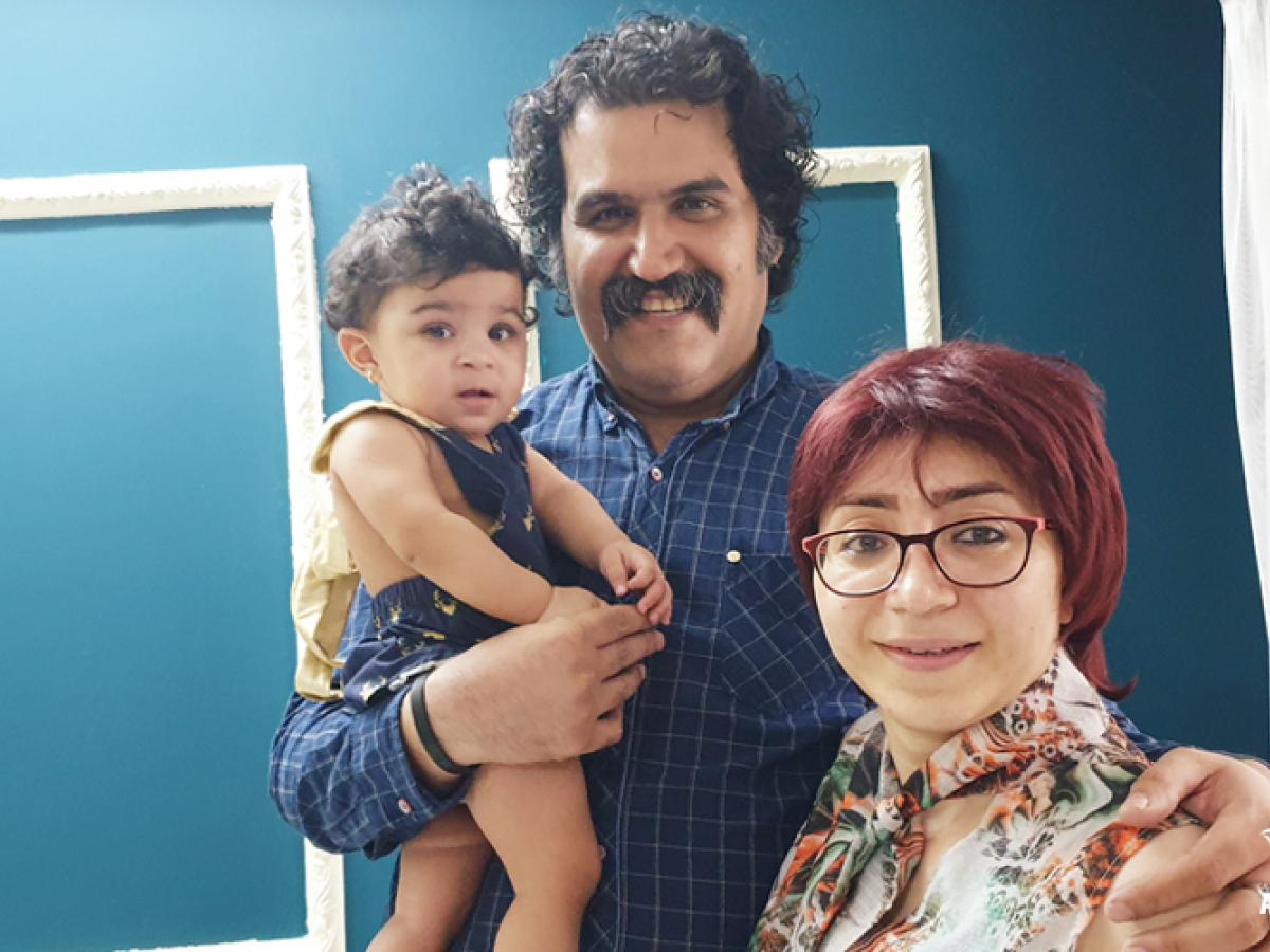 A toddler is held by her father while he stands next to her mother.