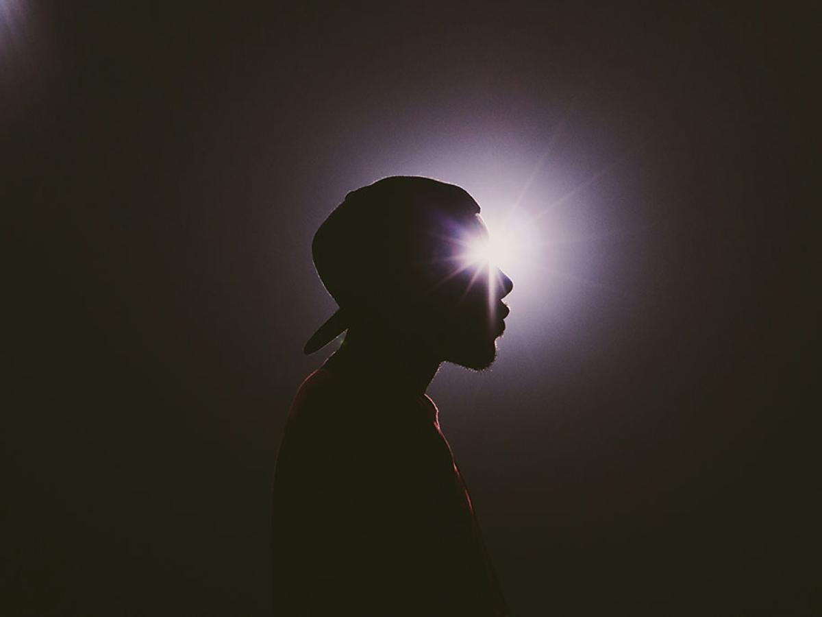 A star burst of light appears to emanate from the eye of a man's head in silhouette. 