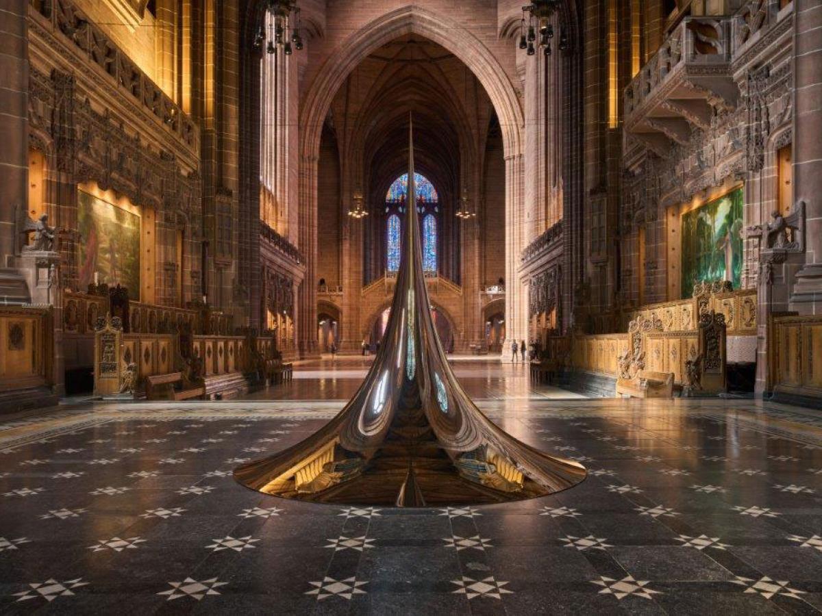 An art structure of a circular peak sits on the chequered floor of a cathedral.