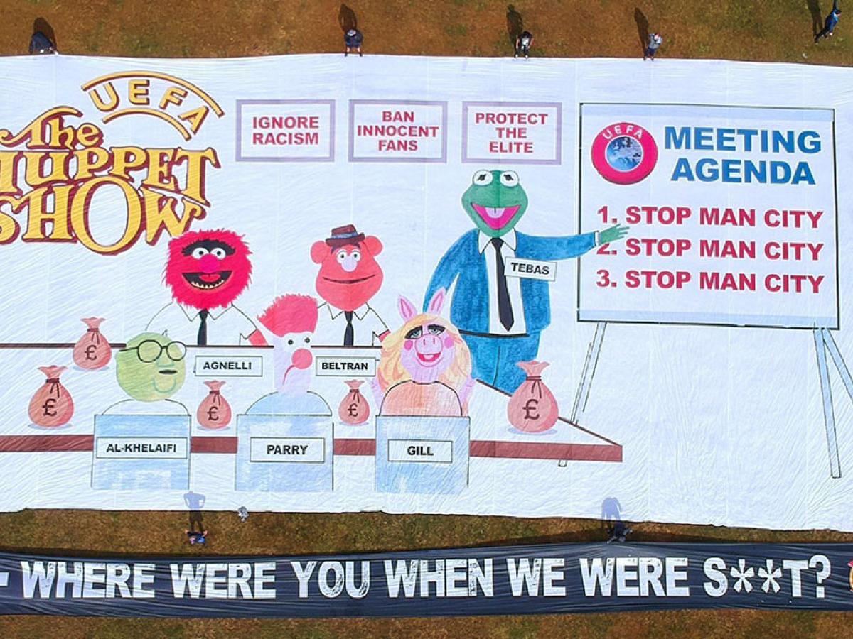 A football support protest banner depicts The Muppet Show logo, a meeting of men in suits and various slogans.