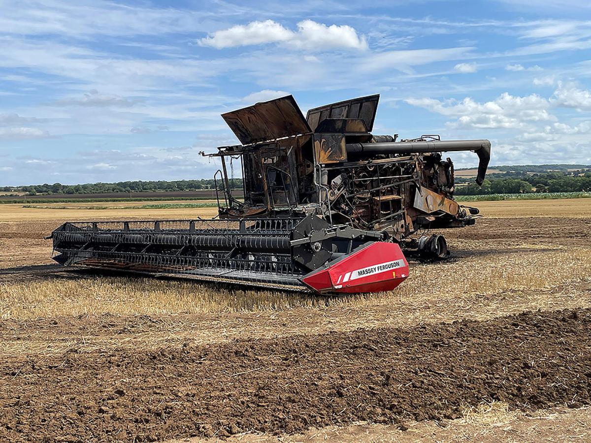 A soot stained burnt-out harvester sits in a recently harvested field.