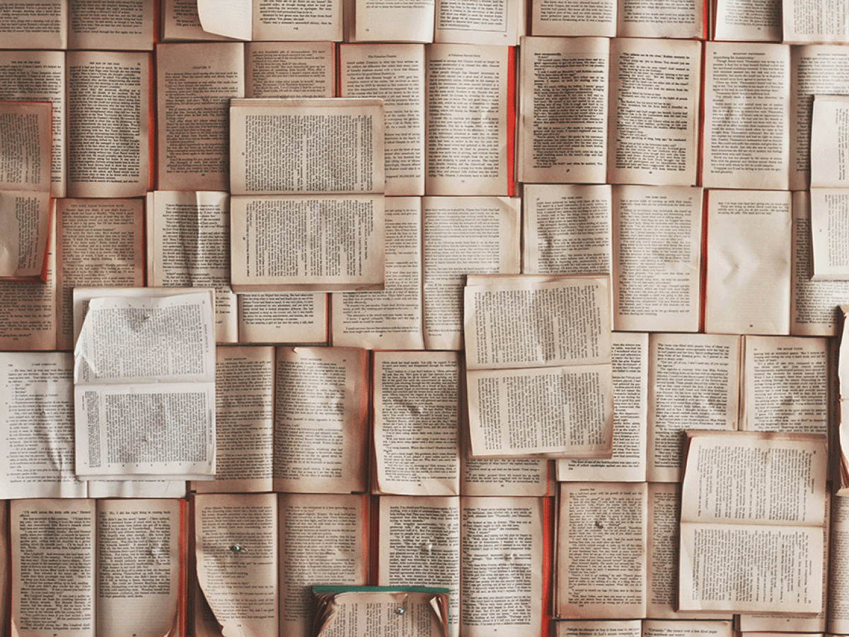 Pages from books are pinned across wall.