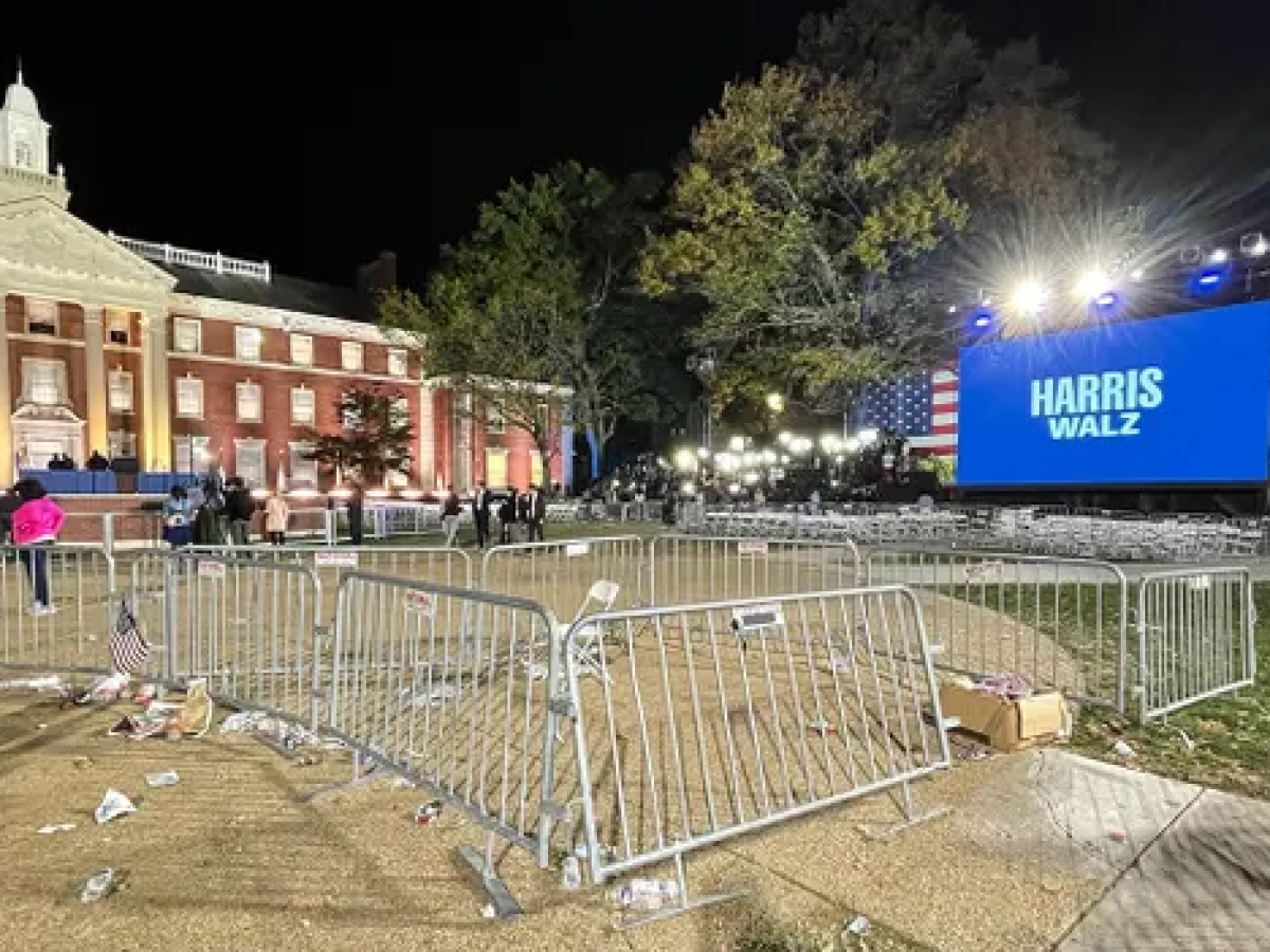 Crowd barrier surround empty space at a night time political rally.