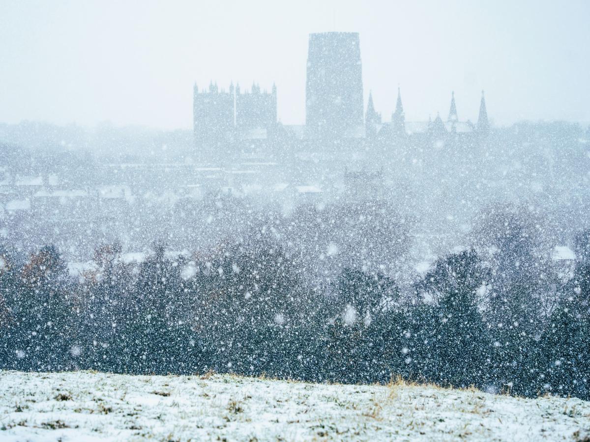 Snow falling pixilates the view from a hill towards Durham Cathedral.