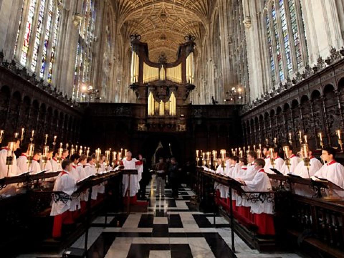 Choristers stand and sing in choir stalls in a church