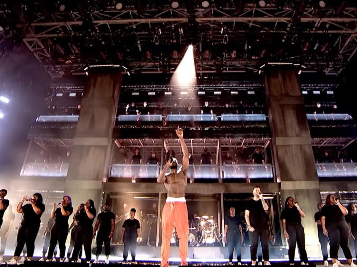 Rapper Stormzy raises a hand to heaven as he sings with a gospel choir on the Glastonbury stage.