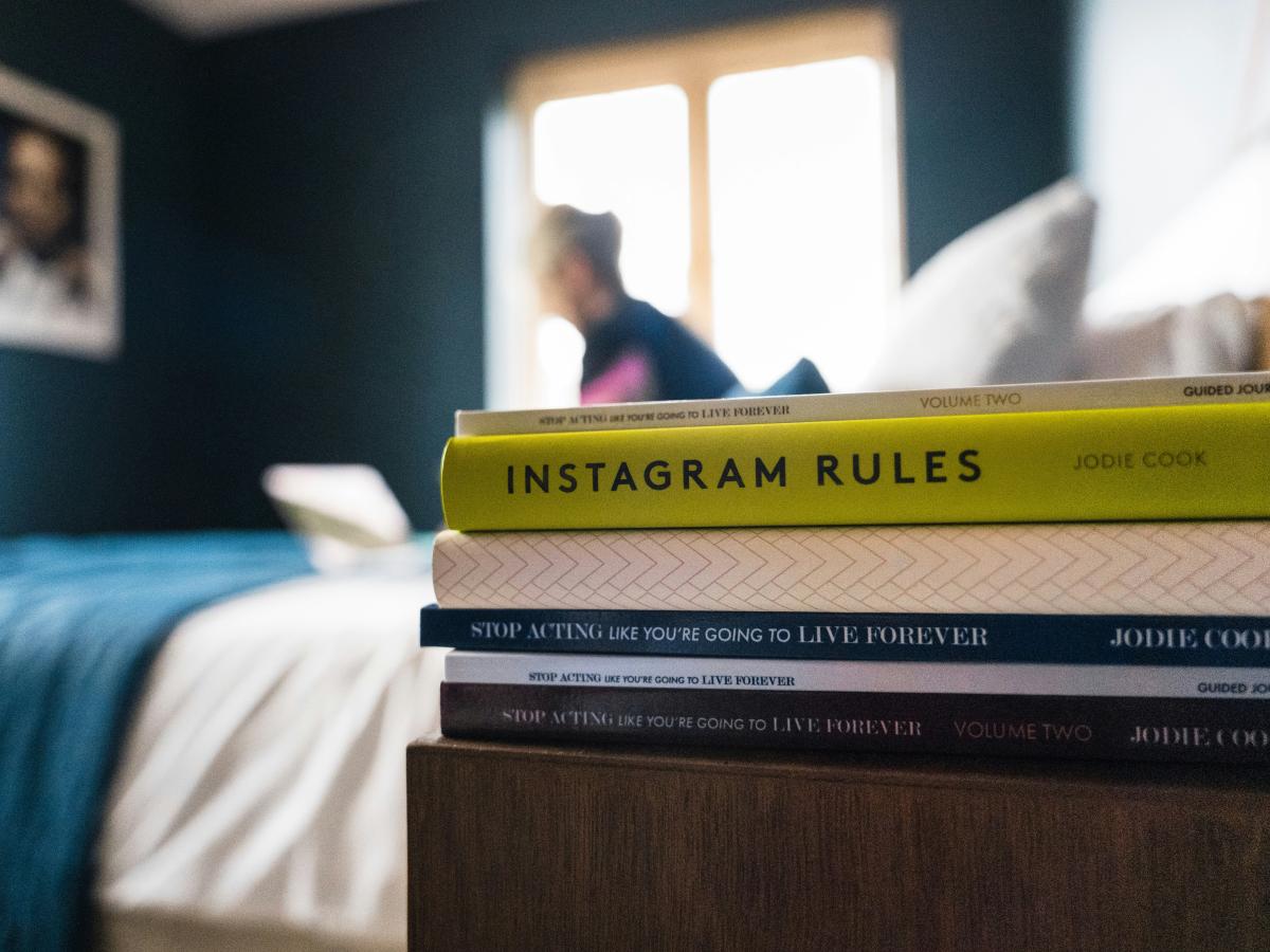 A pile of books on a bedside table.