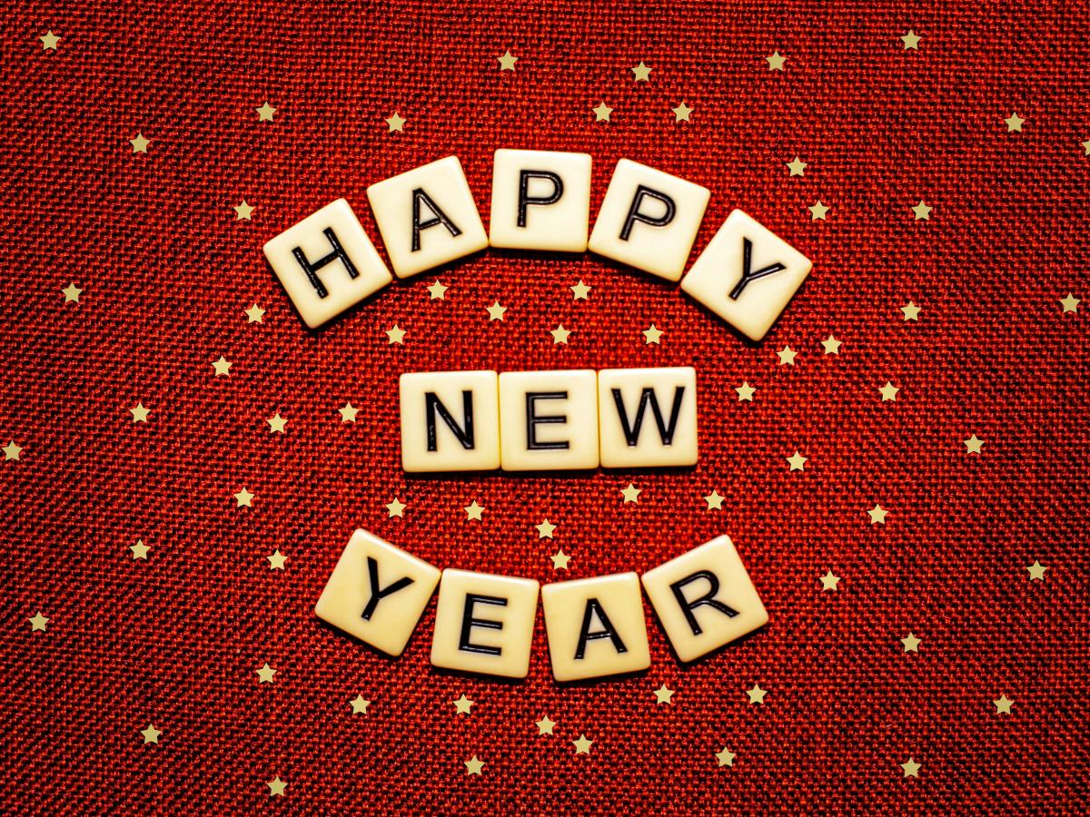 Scrabble letters read 'Happy New Year' against a red starry background.