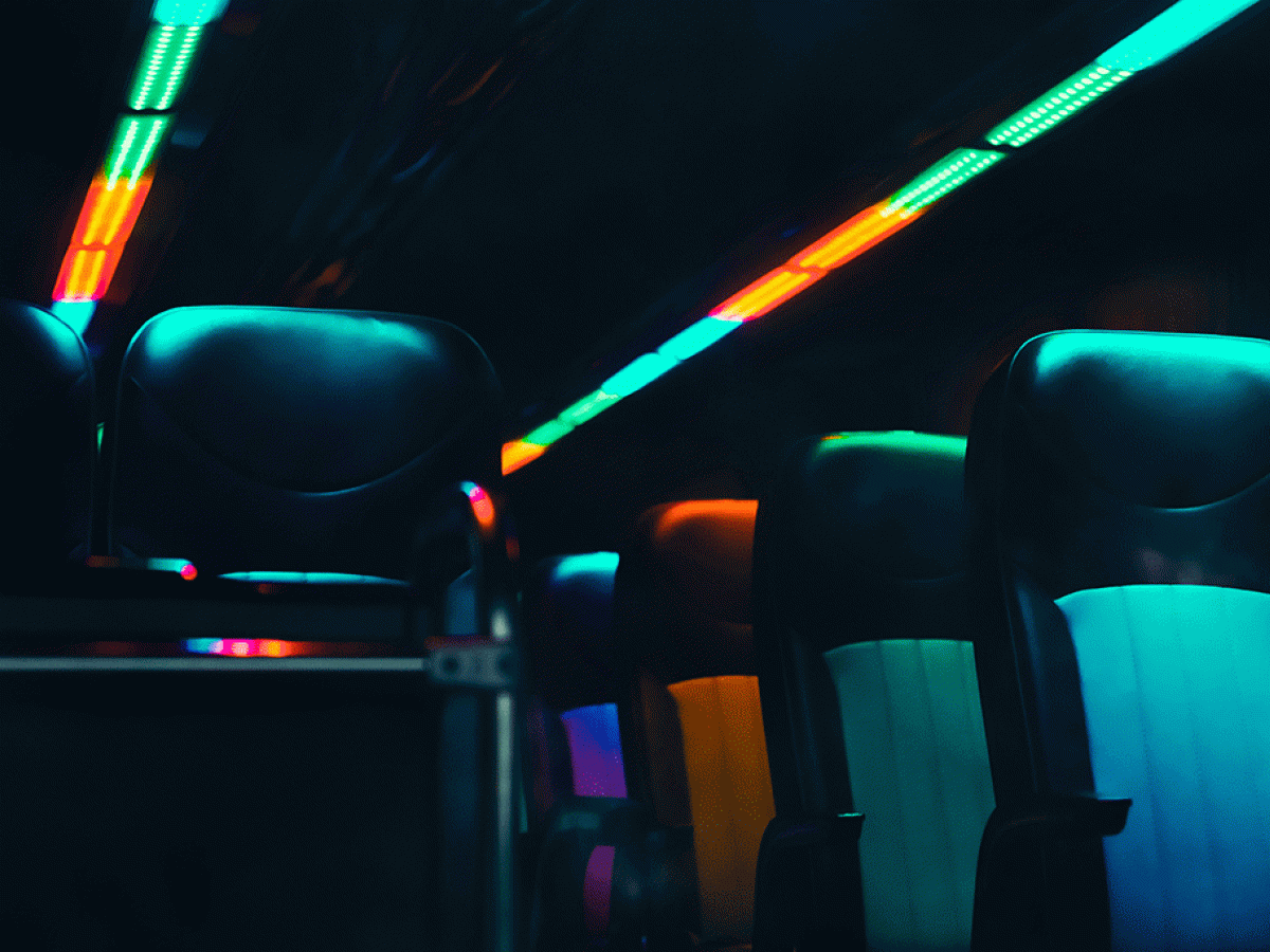 Empty bus seats are lit in dark neon colours.