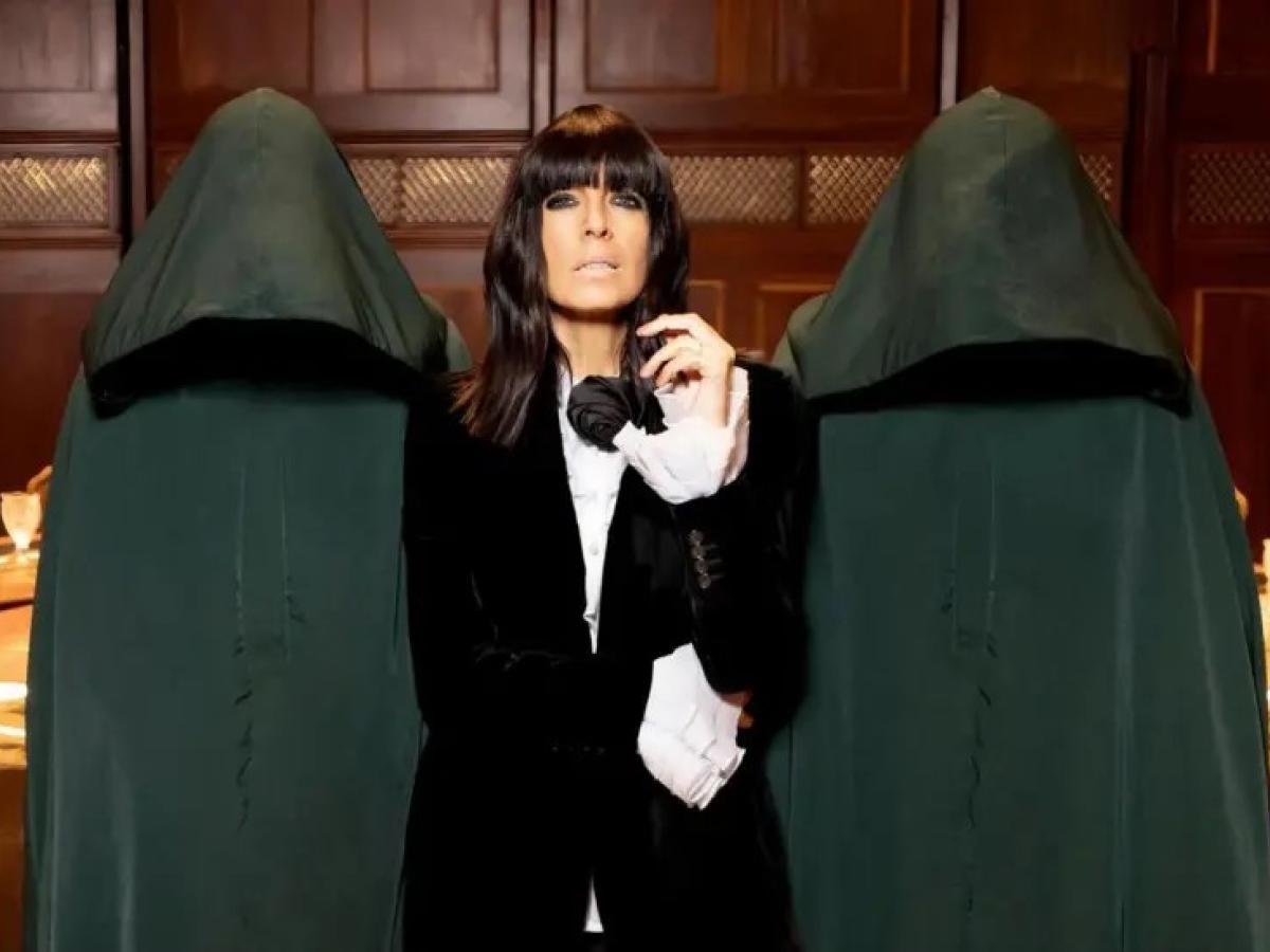 A TV show presenter looks imposing between two hooded figures.