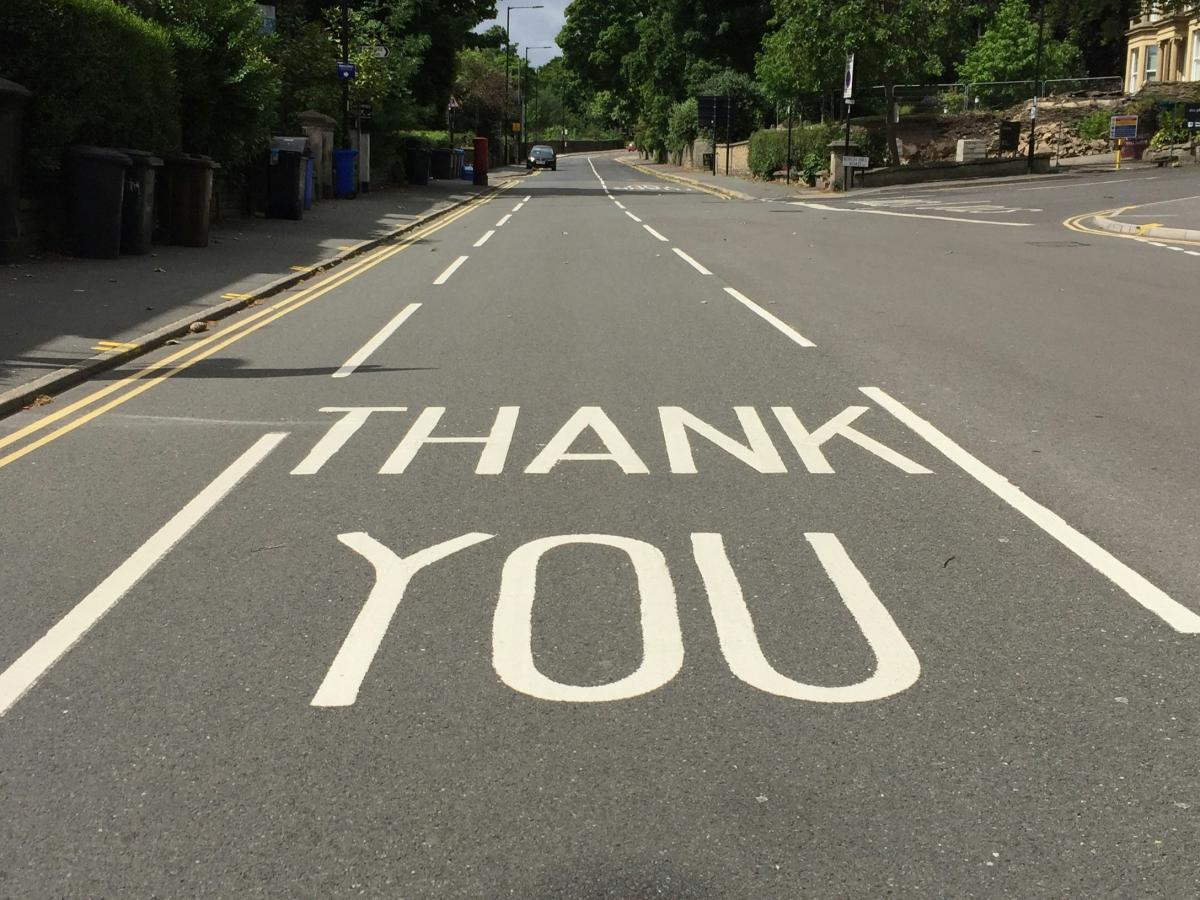 A  painted sign on a road reads 'THANK YOU'