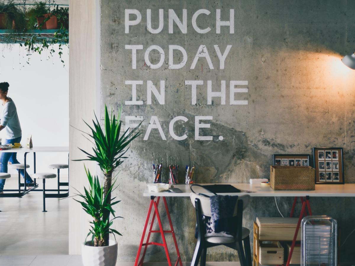 An office wall displays a huge motto reading 'punch today in the face'