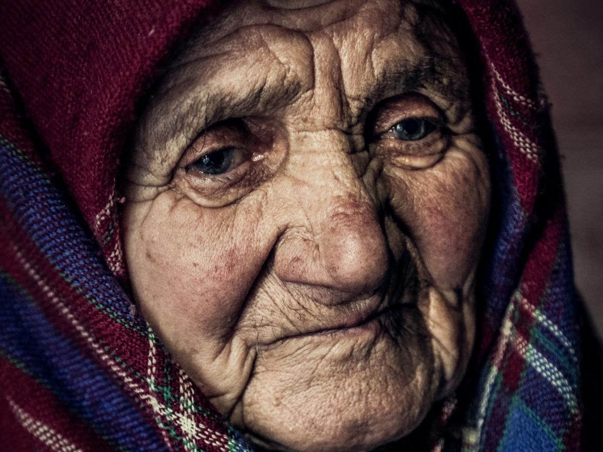 An old woman wearing a shawl looks pensive.