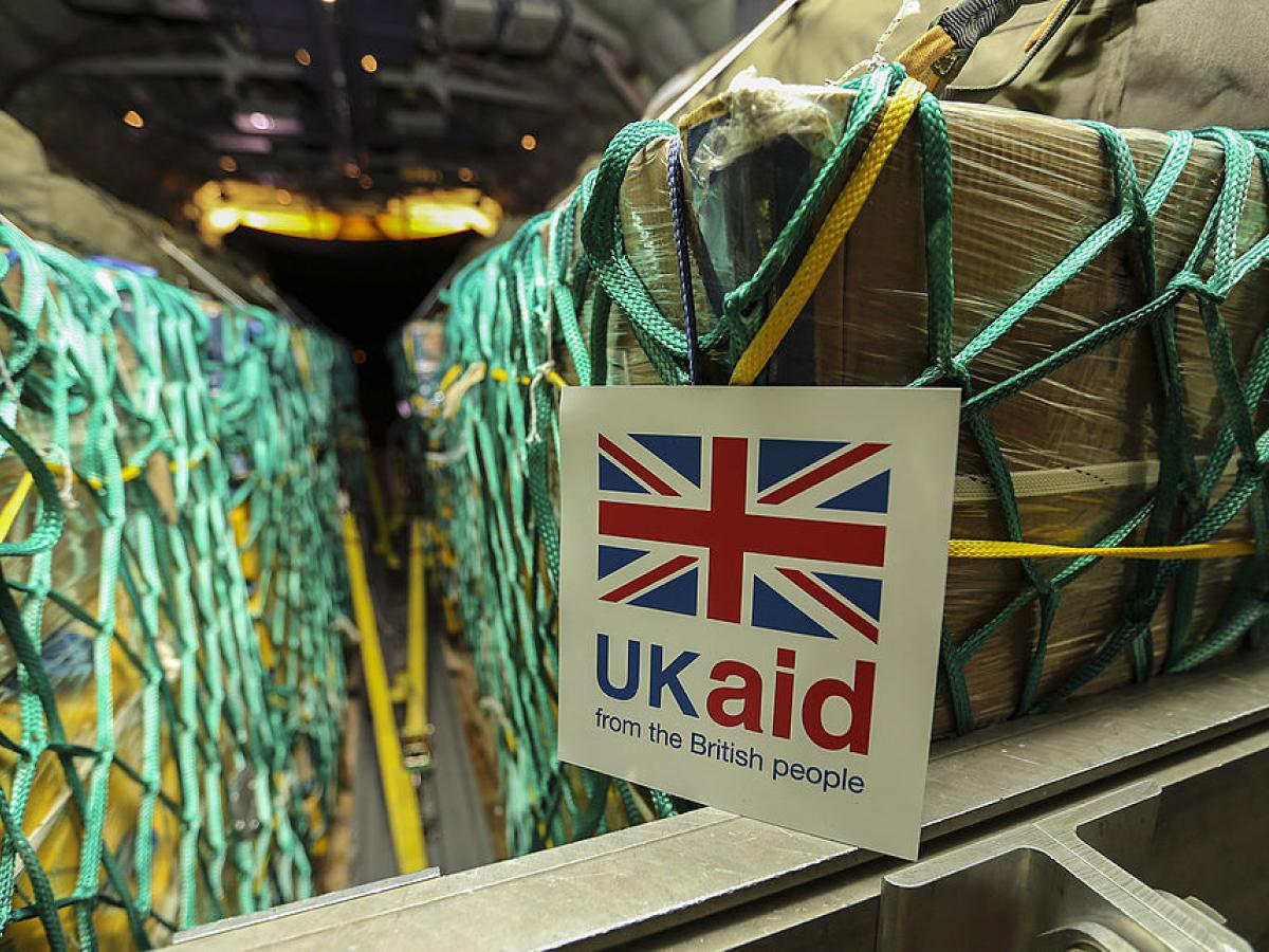 Cargo sits in nets inside a plane, a sign reads 'UK Aid'