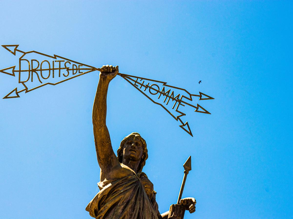 A statue of a woman holding a spear in one hand a lightening bolt in the others that reads: 'Droits de  l'homme'.